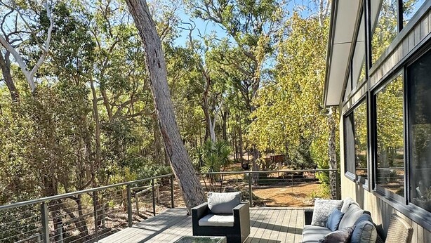 A deck with outdoor furniture, a railing, and trees in the background. - Springdale Gums: Denmark Forest Retreat (Hay)