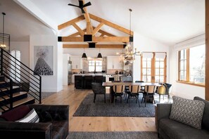 Un espacio habitable amplio con una mesa de comedor, sofás y una escalera.