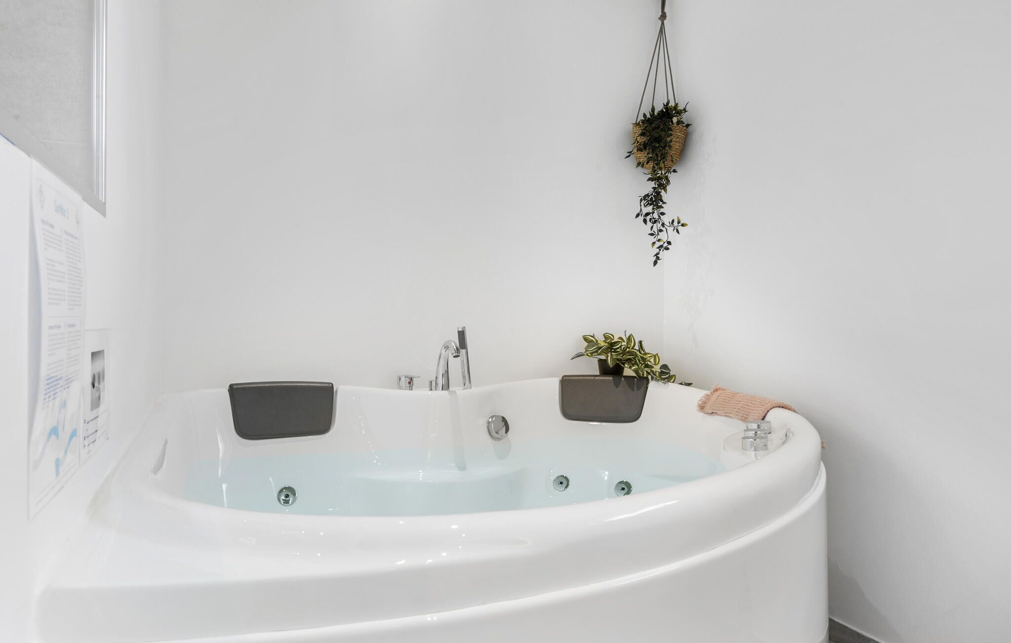 Une salle de bain moderne avec une baignoire sur pieds, deux vasques fixées au mur et une petite plante en pot.