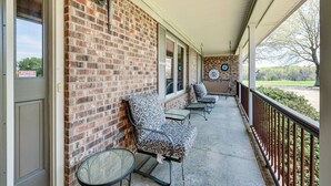 A covered porch with brick walls, a door, and two patterned chairs. - Spacious Mount Pleasant Home w/ Grill & Yard! (Mt Pleasant)