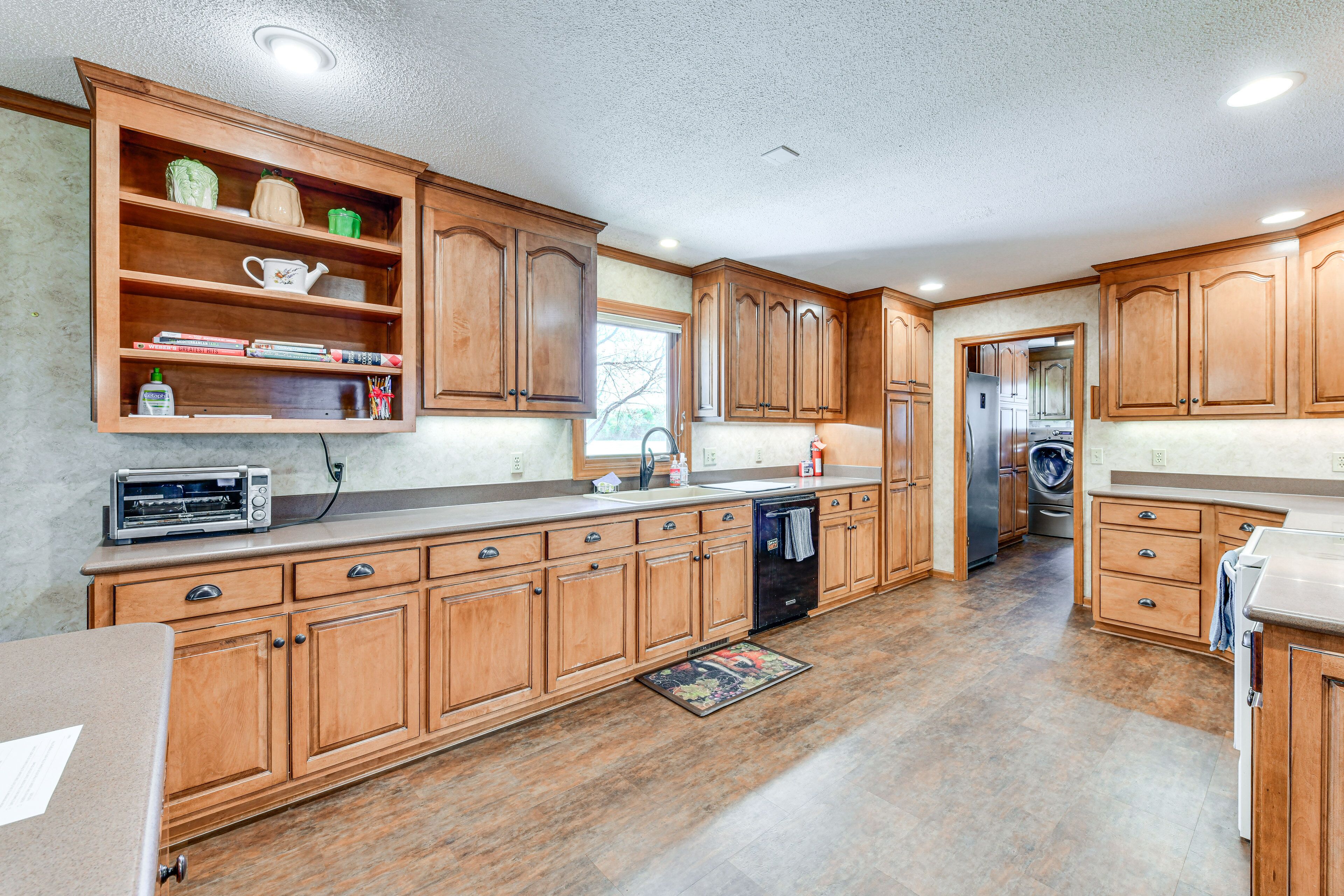 A spacious kitchen with wooden cabinets, a built-in oven, and a dishwasher.