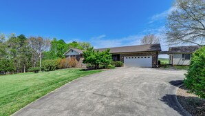 A residential driveway leading to a garage with a brick house and a detached garage. - Spacious Mount Pleasant Home w/ Grill & Yard! (Mt Pleasant)