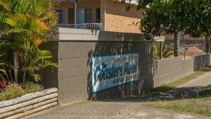 A sign for The Coasters Motel with a brick wall and palm trees. - Coasters 18 - steps from downtown Sawtell (Sawtell)