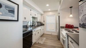 A modern kitchen with white cabinets, a dishwasher, a microwave, a refrigerator, and a stove. - Oceanfront condo with PRIVATE deck. Pet friendly. Just a short walk to town. (Cayucos)