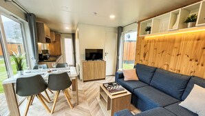 A modern, compact living space with a dining area, sofa, and TV. - Tiny Haus Christas Angler-Oase by Interhome (Riedenburg)
