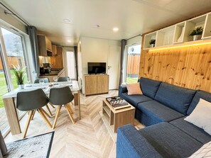 Een moderne, compacte woonruimte met een eethoek, bank en televisie.