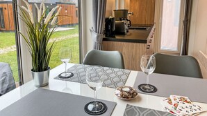 A dining area with a table set for two, a potted plant, and a view of the kitchen and outdoor area. - Tiny Haus Christas Angler-Oase by Interhome (Riedenburg)