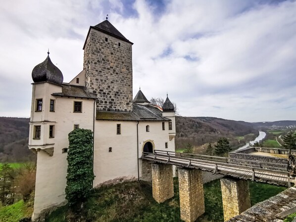 A castle with a stone tower, a bridge, and a river in the background.