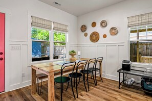 Un comedor con una mesa y sillas de madera, una ventana con persianas y detalles decorativos en la pared.