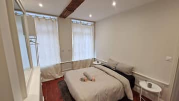 A bedroom with a bed, bedside tables, and a window with curtains.