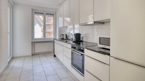 Une cuisine moderne avec des armoires blanches, un comptoir noir et des appareils en acier inoxydable.