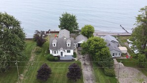 Ein zweistöckiges Haus mit großem Vorgarten, einer Auffahrt und Blick auf das Meer.