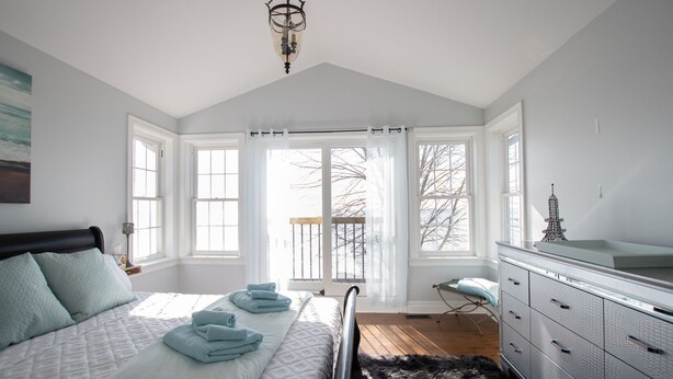 Ein Schlafzimmer mit einem großen Bett, einem Schminktisch und Blick ins Freie durch ein Fenster.