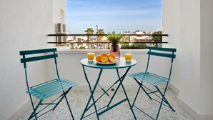 A balcony with two blue chairs, a small table, and a plate of oranges and juice.