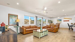 A spacious living room with leather sofas, a wooden coffee table, and a dining area with a table and chairs.