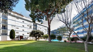 Um hotel com piscina, rodeado por jardins bem cuidados e árvores.