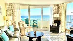 Hotelkamer met balkon, een bank, een stoel, een tafel en uitzicht op zee.