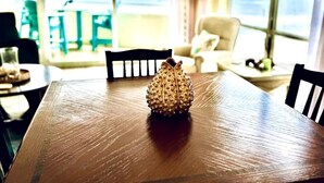 Een eettafel met een decoratief object in het midden, een stoel en een uitzicht door een raam.
