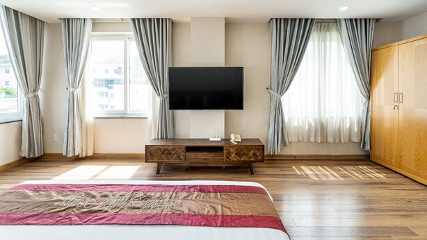 A hotel room with a bed, a TV mounted on the wall, a wooden cabinet, and a wardrobe. - La Palma Boutique Hotel (Ho Chi Minh City)