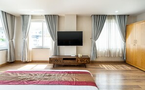 A hotel room with a bed, a TV mounted on the wall, a wooden cabinet, and a wardrobe. - La Palma Boutique Hotel (Ho Chi Minh City)