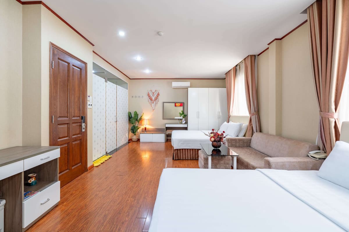 A hotel room with a bed, a sofa, a desk, a wardrobe, and a mirror.