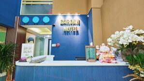 A reception desk with a 'Garden Hotel' sign, a clock, and a decorative plant arrangement. - La Palma Boutique Hotel (Ho Chi Minh City)
