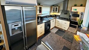 A compact kitchen with a built-in dishwasher, a stainless steel refrigerator, a gas stove, and a microwave. - Sunset 5 -  Southview Holiday Park Skegness (Skegness)