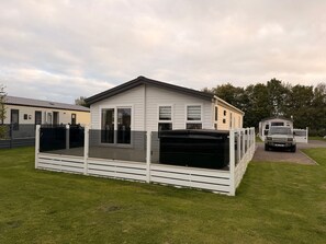 Een stacaravan met een omheind terras, een garage en een oprit.