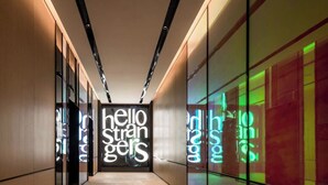 Un couloir au design moderne, agrémenté d’une enseigne lumineuse bien visible sur laquelle on peut lire : « Bonjour, inconnus ».