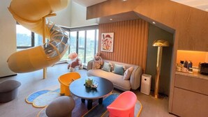 Un salon moderne doté d’un toboggan en spirale original, d’un ensemble de canapés, d’une table basse et offrant une vue sur la ville.