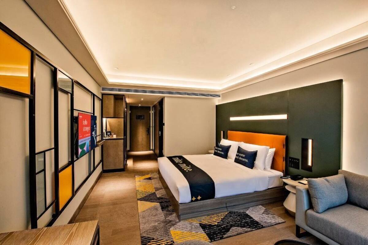 Una habitación de hotel moderna con una cama grande, un sofá, un escritorio y un vestidor.
