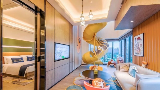 Une chambre d’hôtel moderne dotée d’un plafond incurvé, d’un grand lit, d’un canapé, d’une table à manger et d’un escalier en colimaçon.