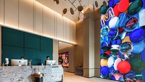 Un espace d’accueil moderne doté d’un comptoir en marbre, de deux postes de travail et d’une œuvre d’art murale aux couleurs vives.