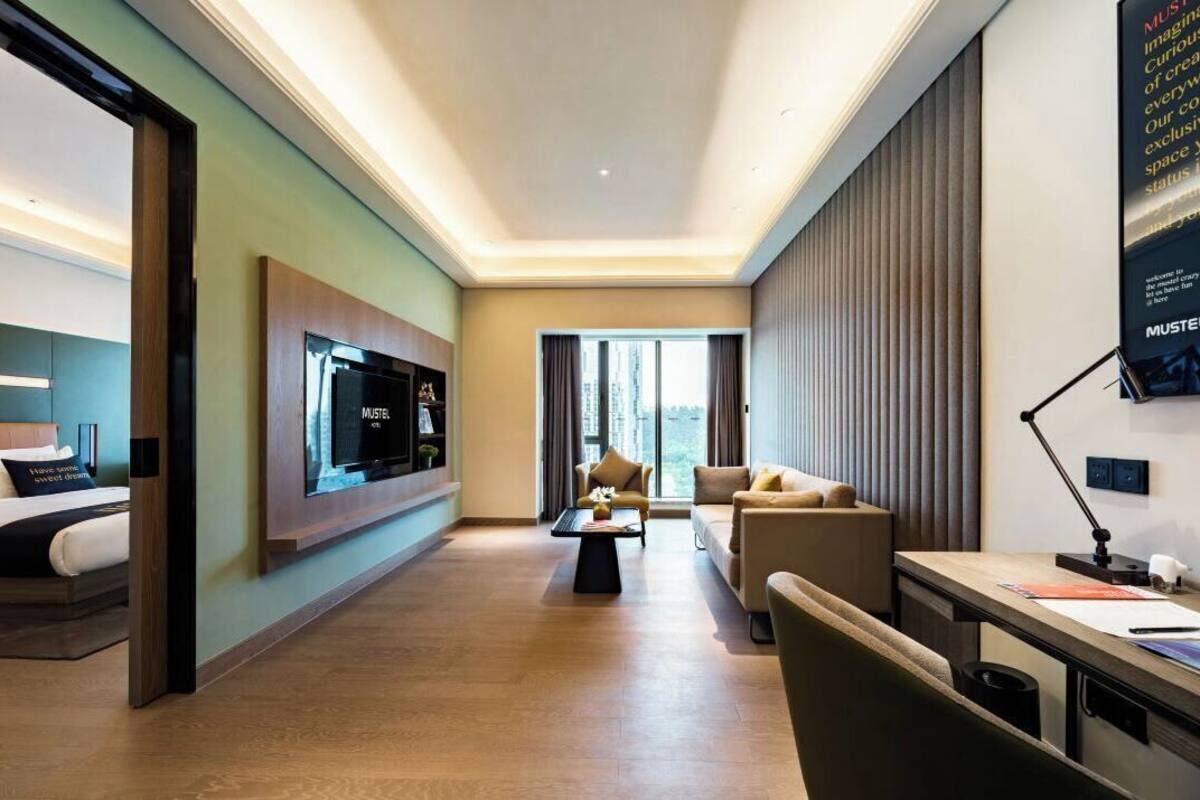 Una habitación de hotel moderna con cama, televisor, escritorio y sofá.