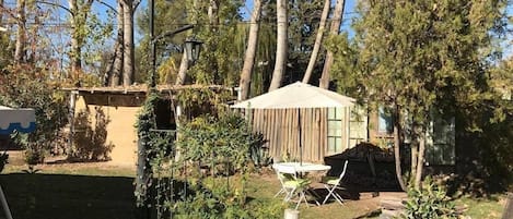 A rustic outdoor area with a wooden structure, a small table with chairs, and a hanging light fixture.