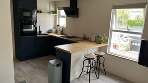 A modern kitchen with dark cabinets, a wooden countertop, a sink, and a window with a view of the outside.