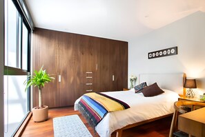 Relax in a spacious room with a large bed, wooden wardrobe, and a potted plant.