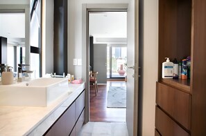 Relax in a serene space with a large bathtub and city views from the balcony.