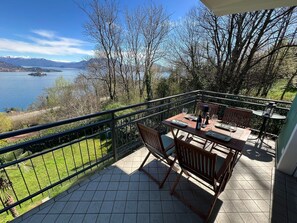 A balcony with a table set for two, overlooking a lake and mountains. - Miralago apartment with amazing lake view in Stres (Stresa)