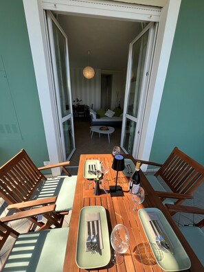 A dining area with a wooden table set for two, a small sofa in the background, and a view into the adjacent room. - Miralago apartment with amazing lake view in Stres (Stresa)