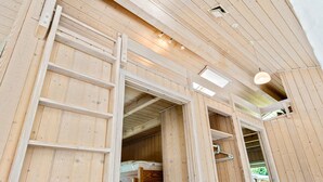 Un intérieur en bois avec un lit superposé, une échelle et une lucarne.