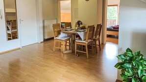 A dining area with wooden chairs and a table, a radiator, and a clock on the wall.