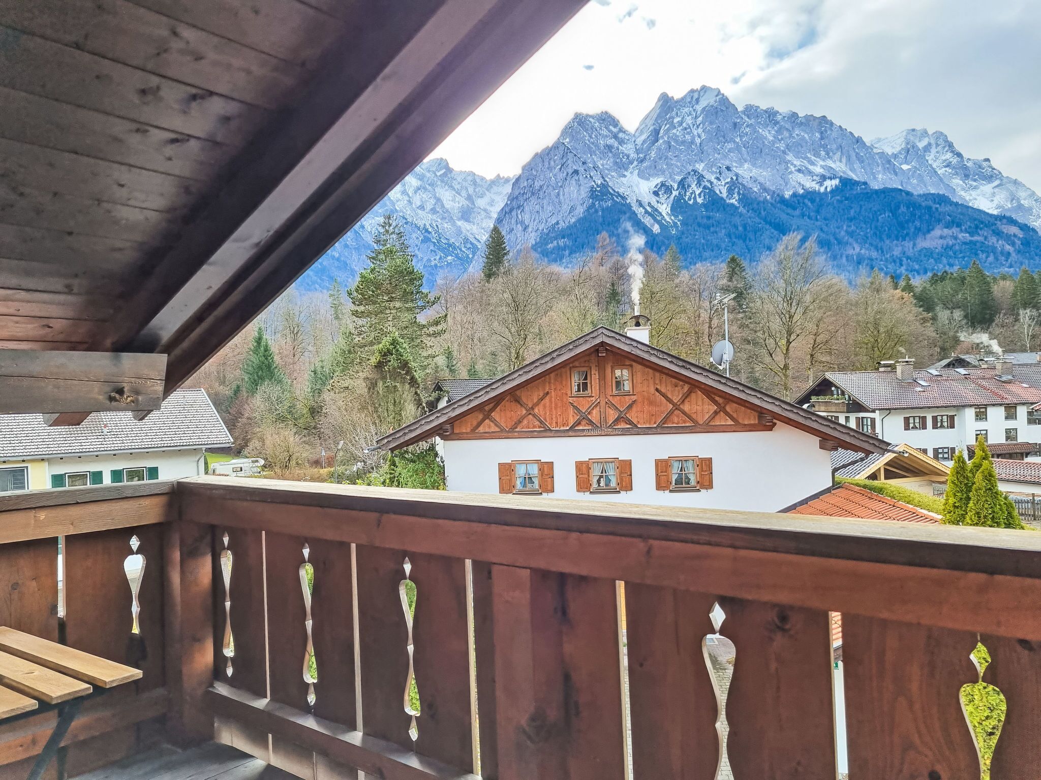 Un balcon en bois offrant une vue sur une chaîne de montagnes et un bâtiment de style chalet traditionnel.