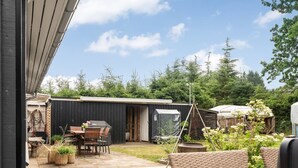 A patio with a table and chairs, a grill, and a covered outdoor area with a shed in the background. - "Juste" - 1.7km from the sea by Interhome (Hals)