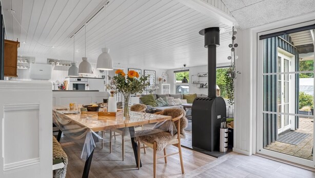 A modern kitchen with a central island, a dining area with chairs, a large window, and a black stove. - "Juste" - 1.7km from the sea by Interhome (Hals)
