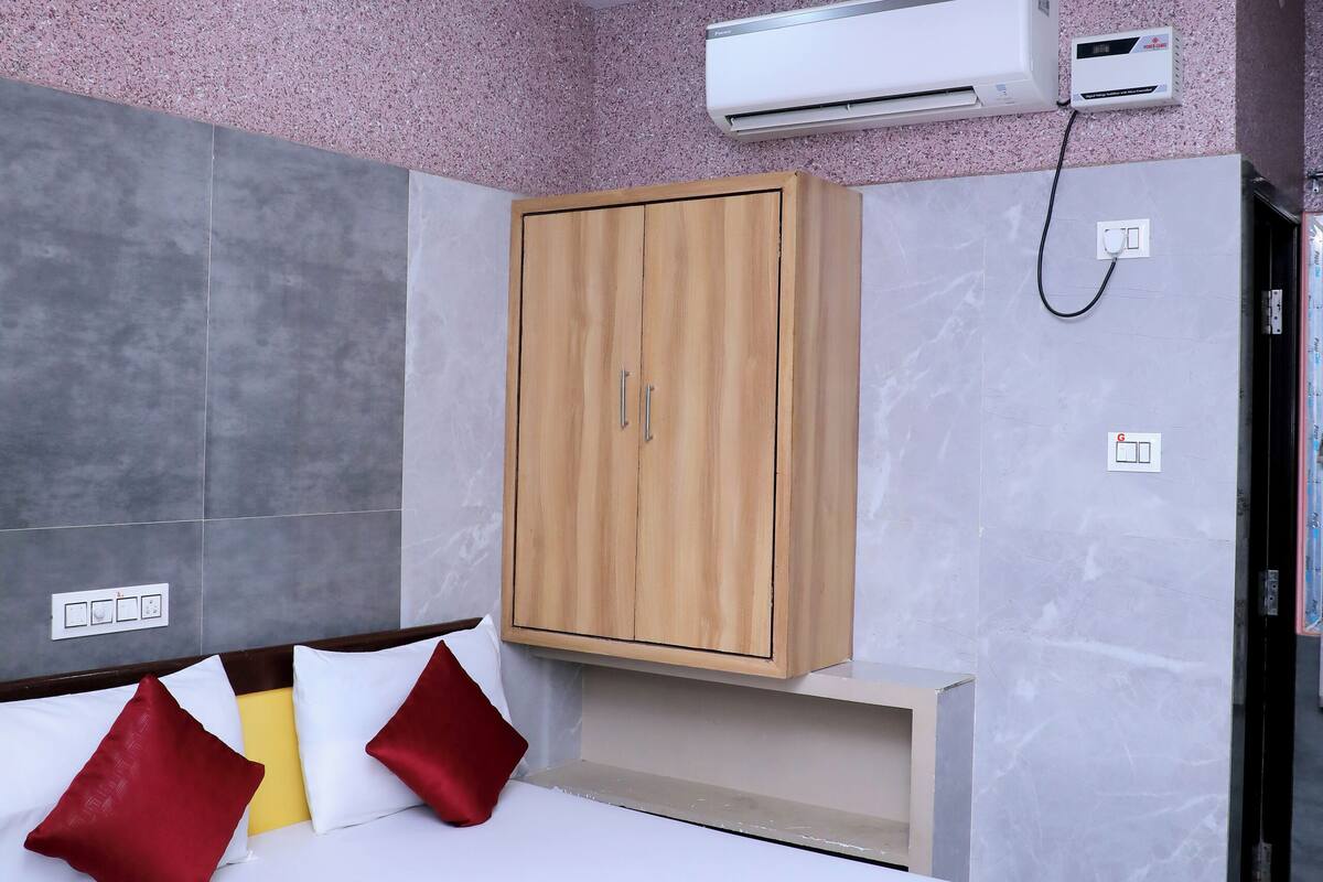 Habitación de hotel con cama, armario de madera, aire acondicionado y ventilador de techo.