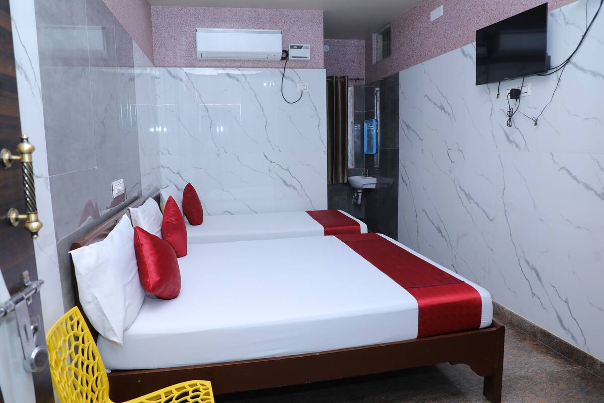 Una habitación de hotel con una cama, un televisor instalado en la pared y un baño visible a través de una puerta abierta.