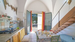 Una cucina con zona pranzo, una scala e una porta aperta che dà sull'esterno.