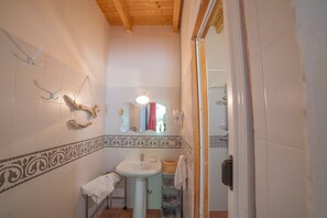 Bathroom features a pedestal sink, mirror, and towel rack.