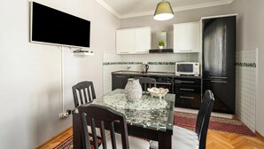 Eine kompakte Küche mit Flachbildfernseher, Mikrowelle und Essbereich mit Glastisch und Stühlen.